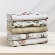 Stack of folded fabric sheets with nature-themed patterns on a light surface.