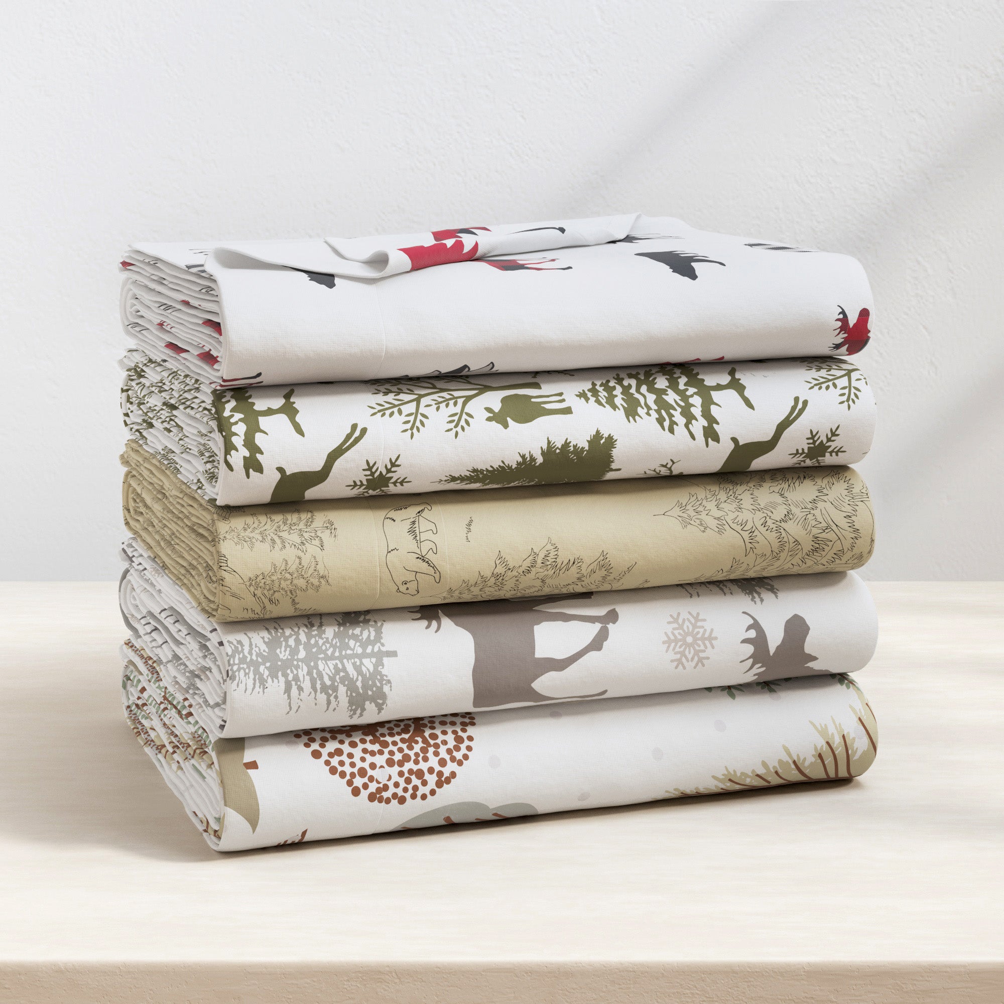 Stack of folded fabric sheets with nature-themed patterns on a light surface.