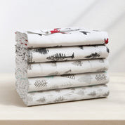 Stack of folded bed sheets with nature-themed design on a light background