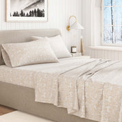 Neatly made bed with beige floral-patterned bedding in a bright bedroom.