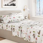 Bed with patterned bedding featuring cabins and trees in a bedroom setting.