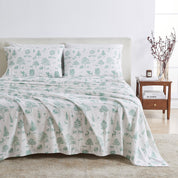 Bedding set with green tree and deer pattern on a bed in a bedroom setting.