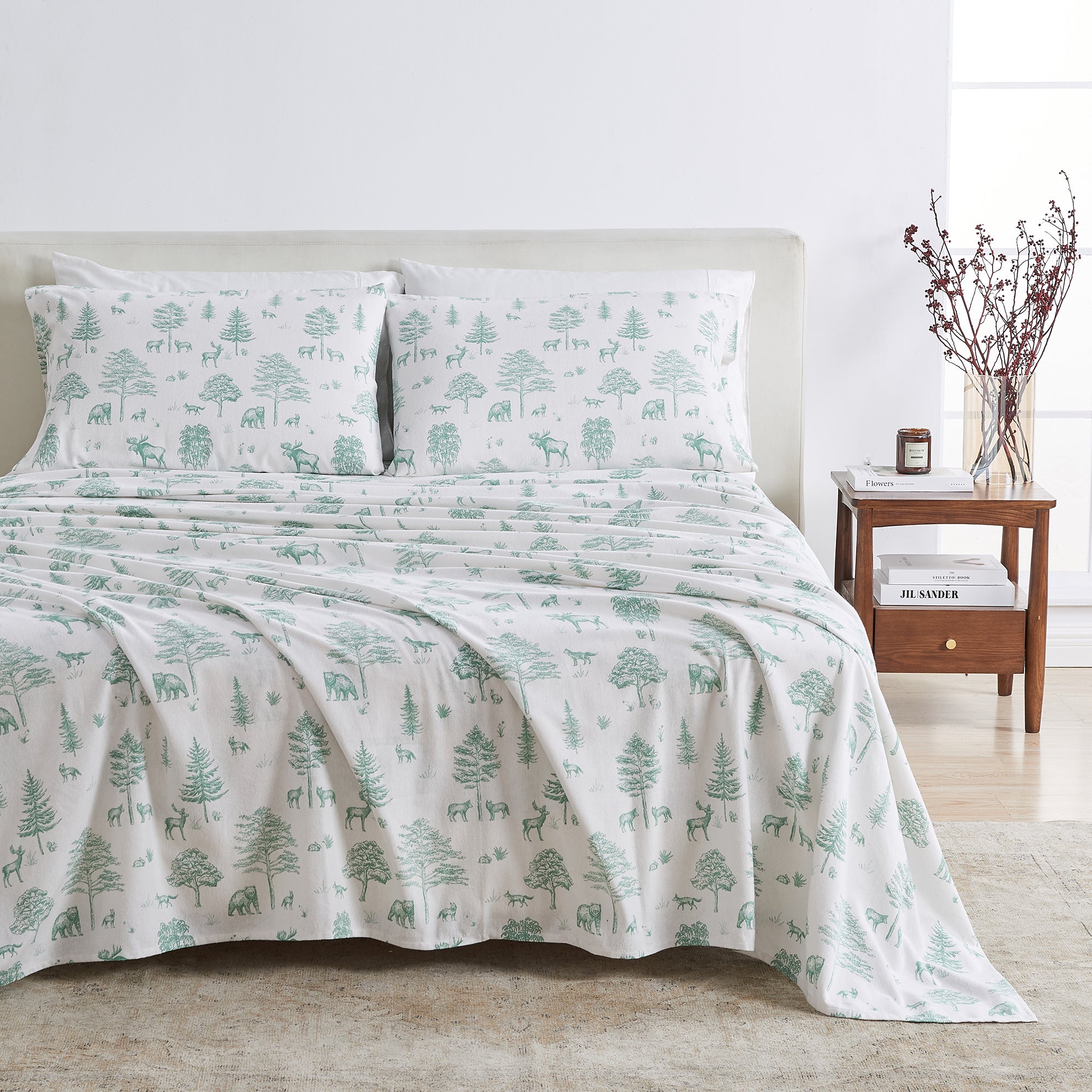 Bedding set with green tree and deer pattern on a bed in a bedroom setting.